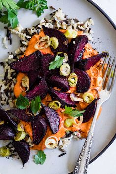 a white plate topped with sliced beets and carrots next to a silver fork