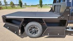 the back end of a black truck parked in a parking lot next to another vehicle