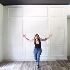 a woman standing in an empty room with her arms spread out and hands raised above her head