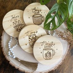 four wooden coasters with coffee designs on them sitting on a table next to a plant