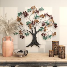 a metal tree sculpture sitting on top of a table next to vases and other items