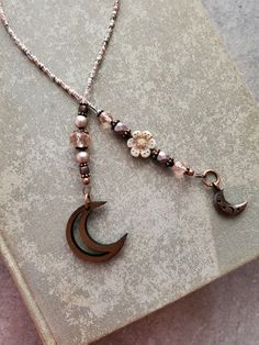 a necklace with pearls and beads hanging from it's side on a bookmark