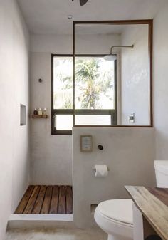 a bathroom with a toilet, sink and window in the wall next to it's wooden floor