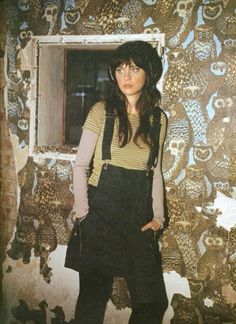 a woman standing in front of a wall with owls on it's walls and wearing overalls