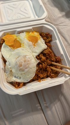 two plastic containers with food in them and chopsticks sticking out of the top