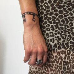 a woman's hand with a tattoo on her left wrist and an iron chain attached to it