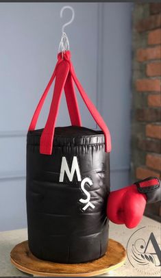 a boxing bag cake on a plate with a pair of red gloves hanging from it