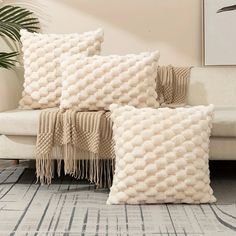 two white pillows sitting on top of a couch next to a plant in a living room