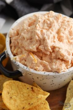 a white bowl filled with chicken salad next to tortilla chips