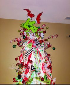 a christmas tree made out of candy canes and other holiday decorations is hanging on the wall