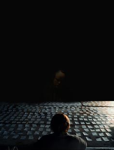 a person standing in front of a wall with squares on it and looking at the ground