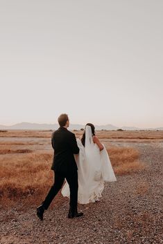 a bride and groom walking in the desert