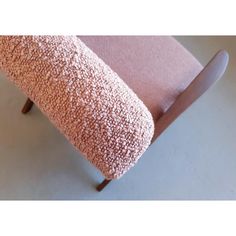 a close up of a pink chair with a wooden frame and arm rest on the floor