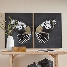 two paintings on the wall above a table with vases and flowers in front of them