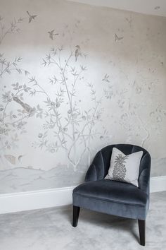 a blue chair sitting in front of a wall with birds and flowers painted on it