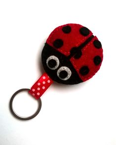 a red and black ladybug key fobring on a white surface with polka dots