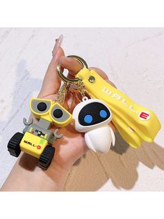 a person holding several different key chains in their hand, including one with a robot on it