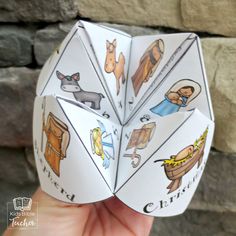 a hand holding an origami dice with pictures of animals and people on it