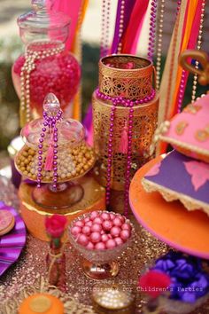 a table topped with lots of candy and candies covered in pink, orange and gold