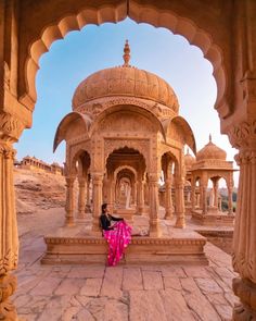 a man and woman standing in front of an ornate building with arches on the sides