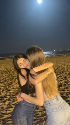 two girls hugging on the beach at night