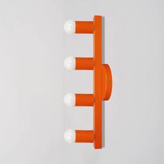 an orange and white wall mounted light fixture with three bulbs on each side of it