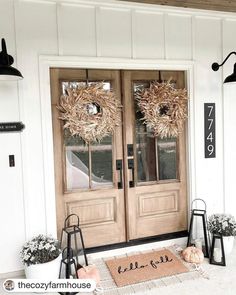 the front door is decorated with wreaths and lanterns