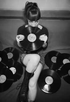 a woman sitting on the floor with many records