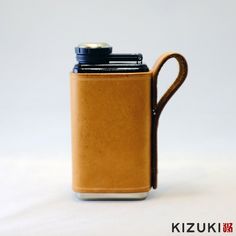 a brown leather flask with a black cap on it's top and handle