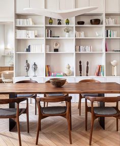 a dining room table and chairs in front of bookshelves with shelves behind them