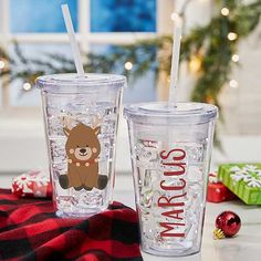 two tumblers sitting on top of a table next to christmas decorations