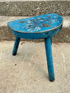 an old blue stool sitting on concrete steps