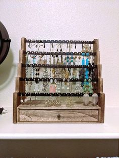 a wooden rack with several pairs of earrings on it and a wall clock in the background