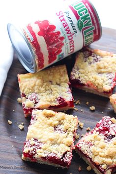 strawberry crumbler bars are on a cutting board next to a can of soda