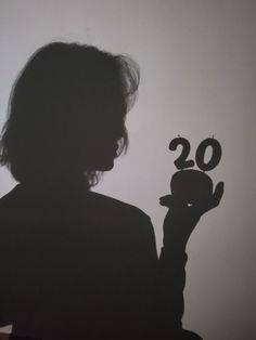 the silhouette of a person holding a small clock in their hand with the number 20 on it