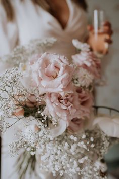 a bride holding a bouquet of flowers in her hand and a glass of wine on the other side