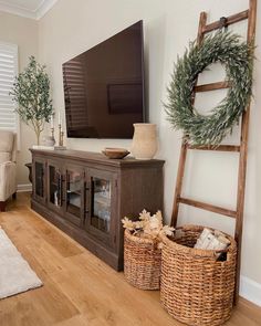 a flat screen tv sitting on top of a wooden cabinet in a living room next to a ladder