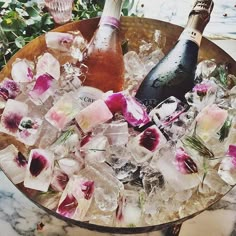 an ice bucket filled with flowers and two bottles of wine sitting on top of it