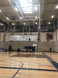 an indoor basketball court with people sitting on the bench