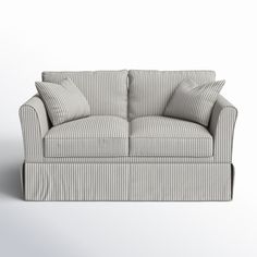 a white and gray striped couch with pillows on it's back end, facing the camera