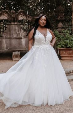 a woman in a white wedding dress posing for the camera with her hands on her hips