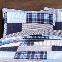 a bed with blue and white plaid comforter on it's side, in front of a wooden headboard