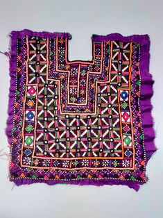 a purple cloth with an intricate design on the front and side, sitting on a white surface