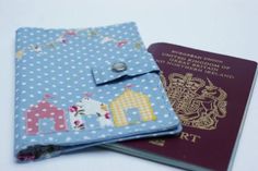 a passport case with a blue polka dot design and a red british passport sitting next to it