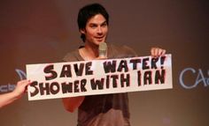 a man holding up a sign that says save water shower with an i am on it