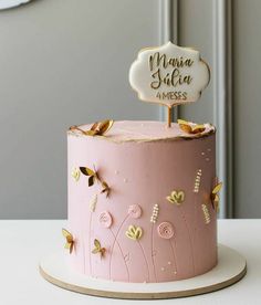 a pink cake with gold butterflies on top and a name plate that says mama julia 4 messes