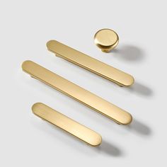 three brass handles and two knobs on a white surface