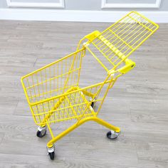 a yellow shopping cart sitting on top of a hard wood floor