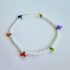 a white beaded bracelet with multicolored beads and small plastic flowers on it