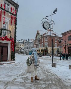 a woman is standing in the middle of a snowy street with christmas decorations on it